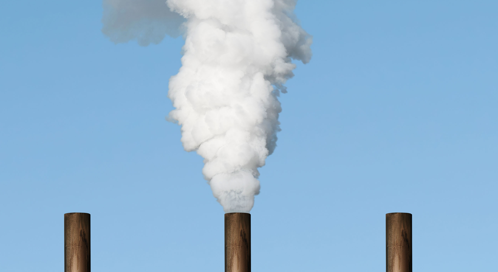 Three large chimneys, with one releasing a white cloud of smoke