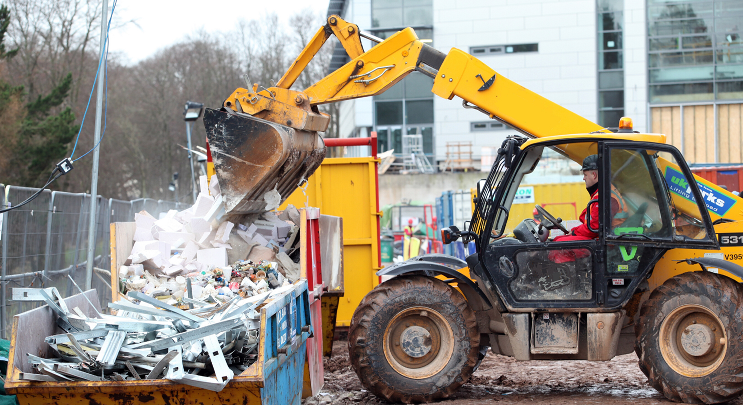 Construction worker using tipper to sump construction waste in a skip