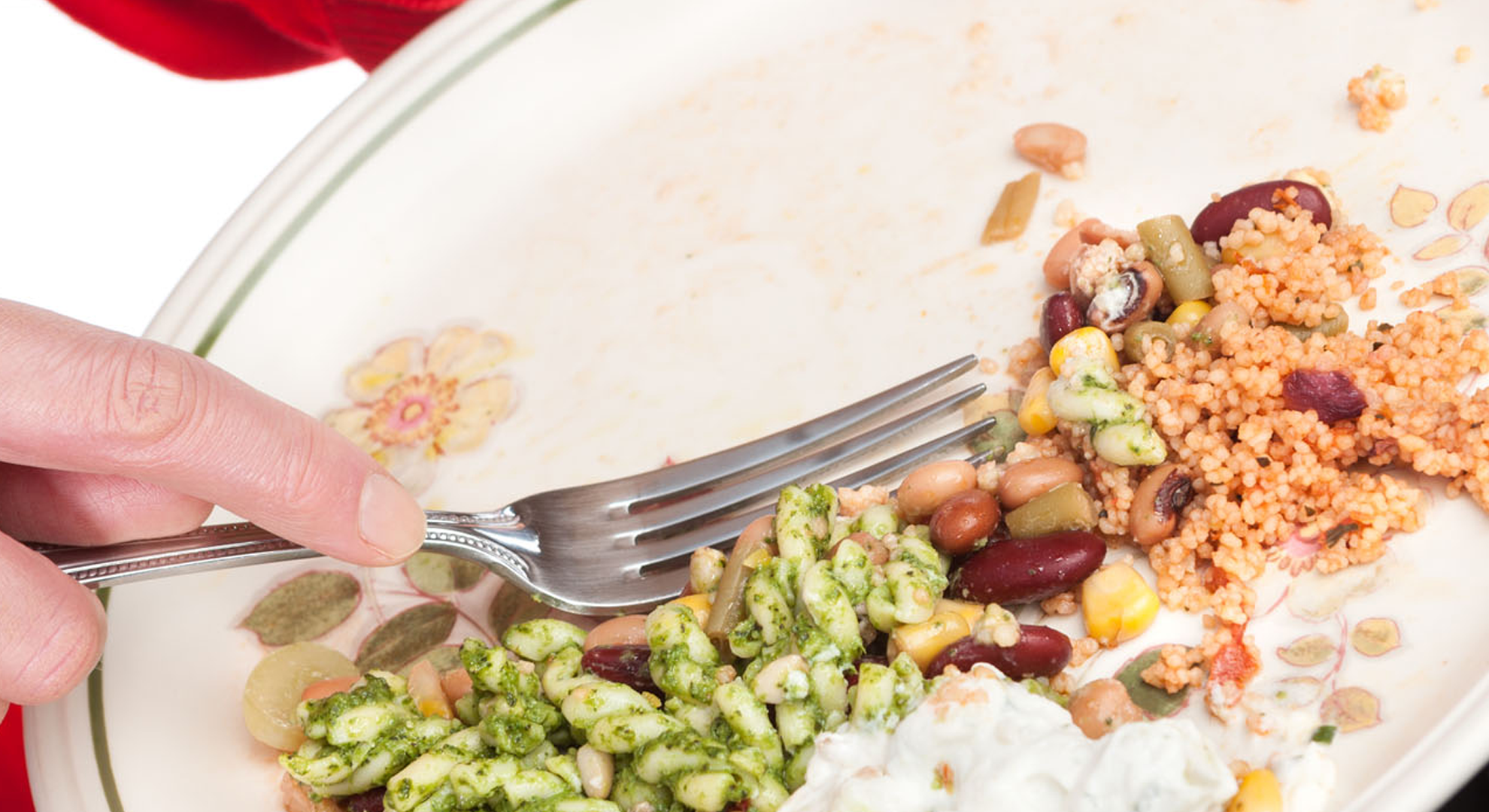 A person scraping food waste from a plate