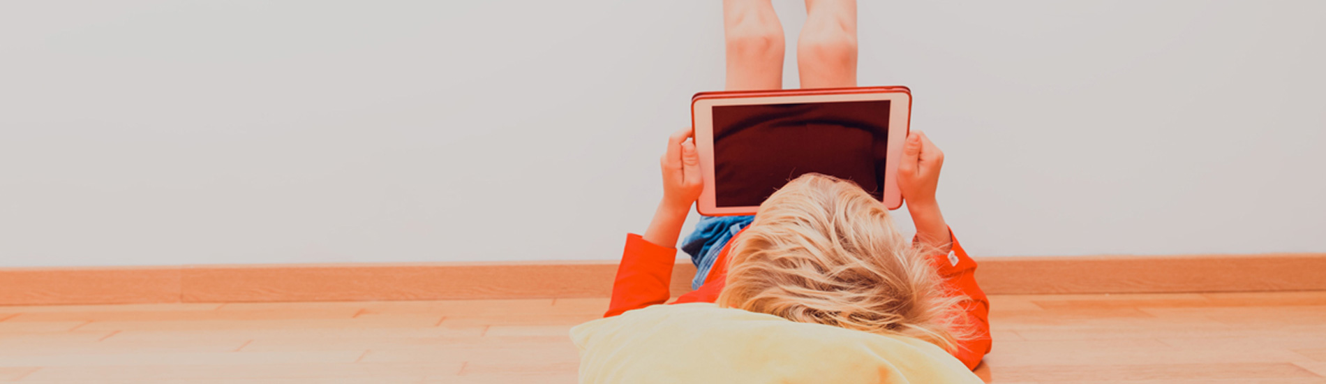 A young person laying on their back looking at a tablet device