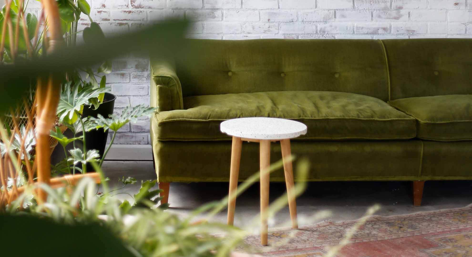 Green sofa and three legged stool with white top
