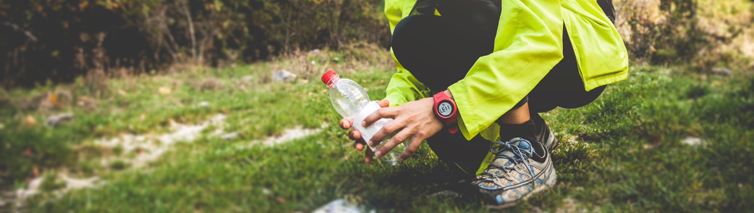 A person picking up a plastic bottle that has been littered