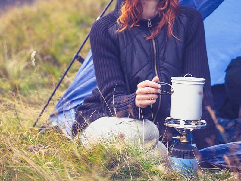 a person sitting outside a tent using a stove