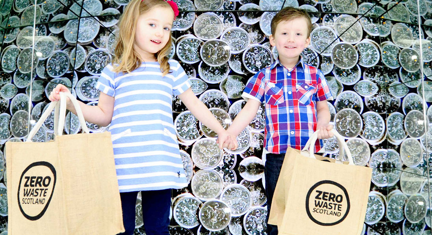 Two young children with reusable carrier bags