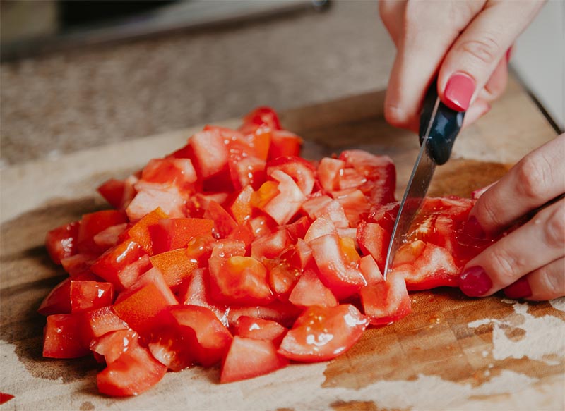 a person chopping up tomatoes on a board
