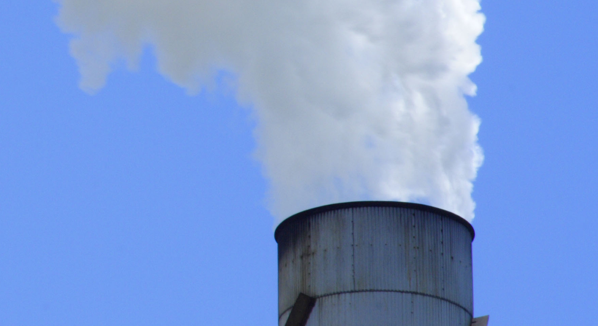 A large chimney releasing a white cloud of smoke