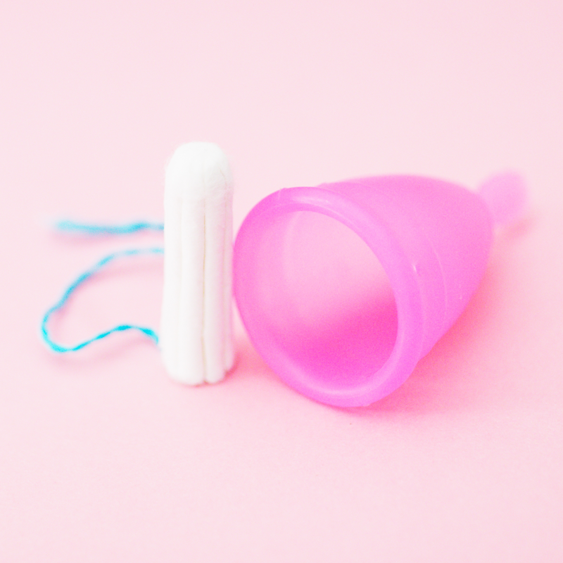 A disposable menstrual sanitary product alongside a reusable menstrual moon cup sanitary product