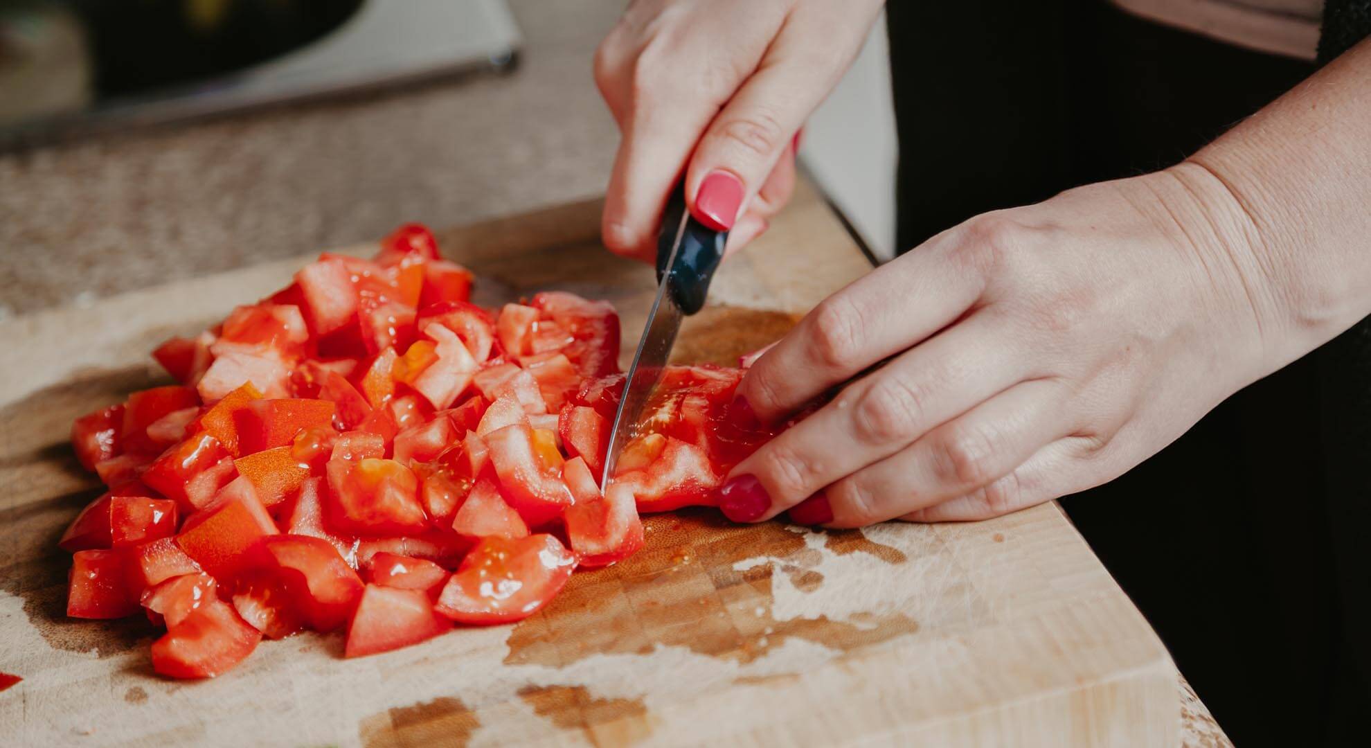 a person chopping up tomatoes on a board