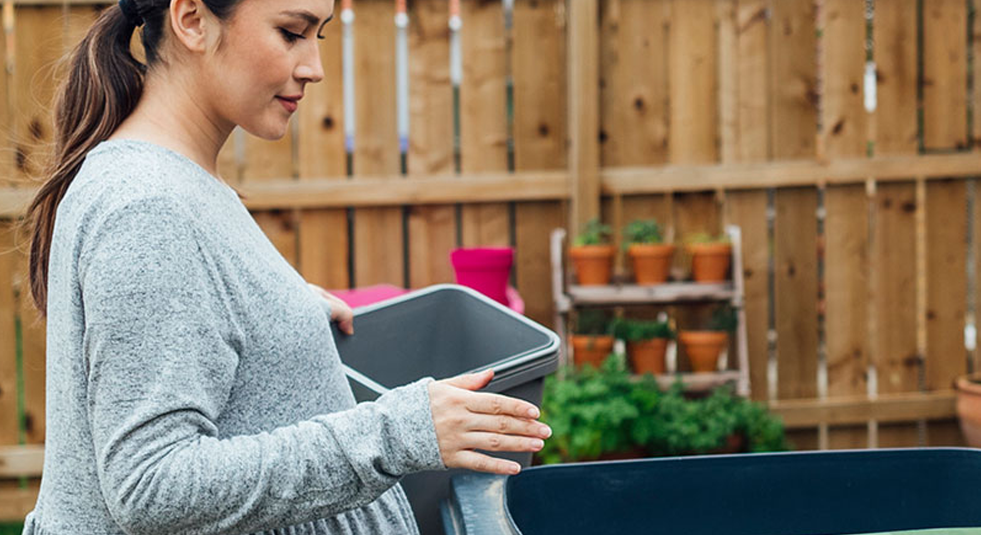 A person standing in front of recycling bins