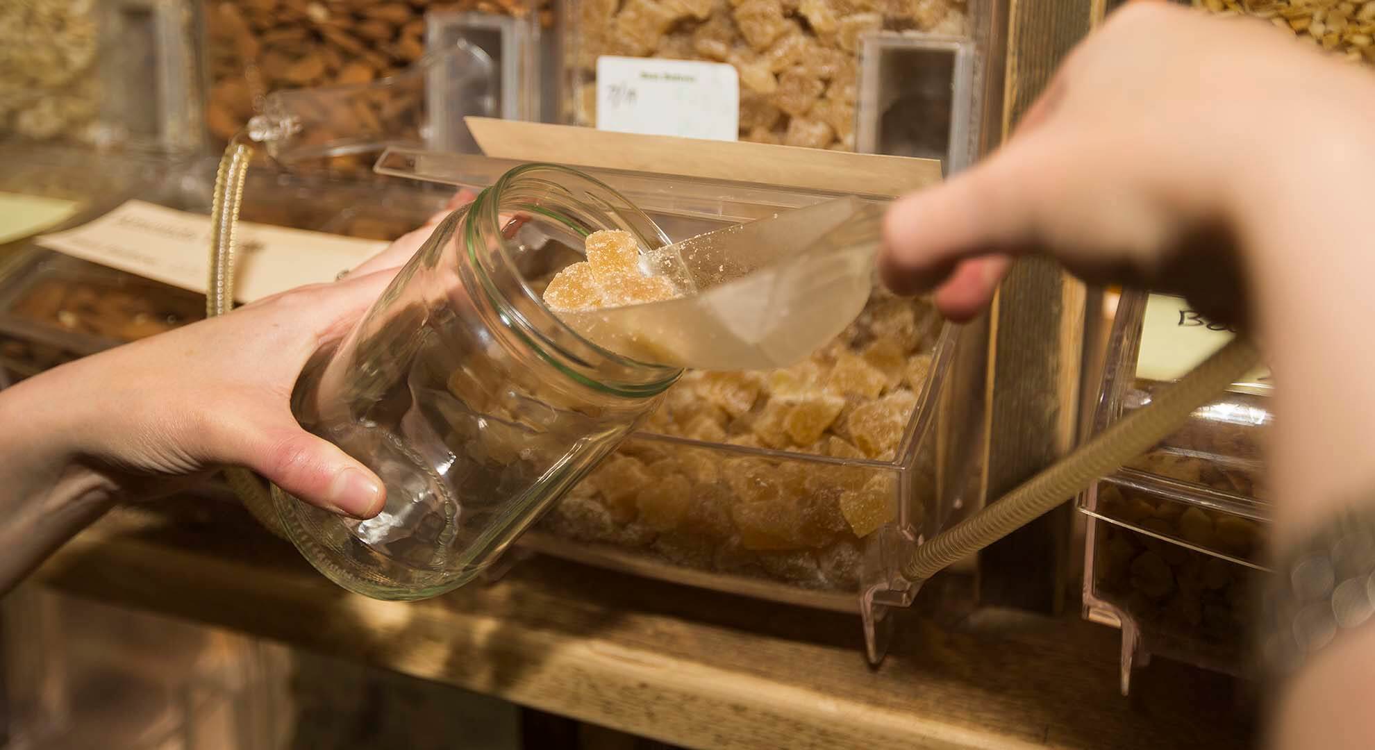 Person filling up a reusable jar at a zero waste refill store