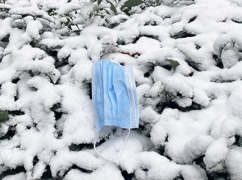 Photo of a single-use face covering littered in the snow