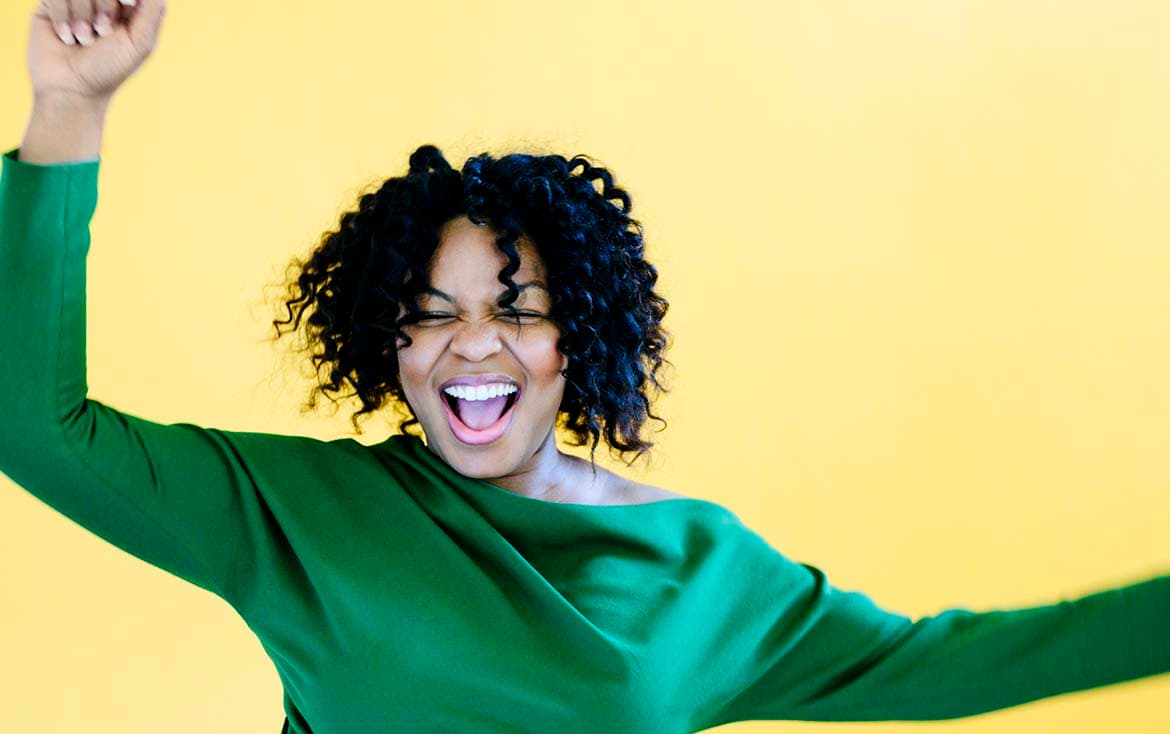 Photo of woman in a green top looking happy against a yellow background.jpeg