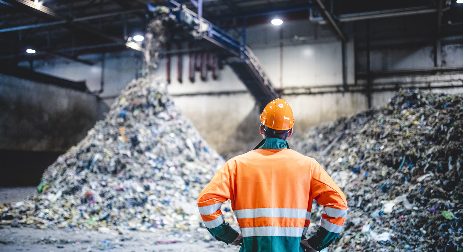 A person standing in front of piles of recycled material at a material recovery facility