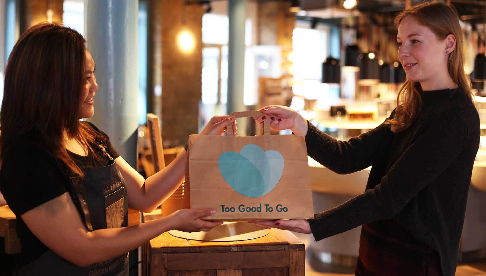Woman collecting a Too Good To Go bag from a cafe