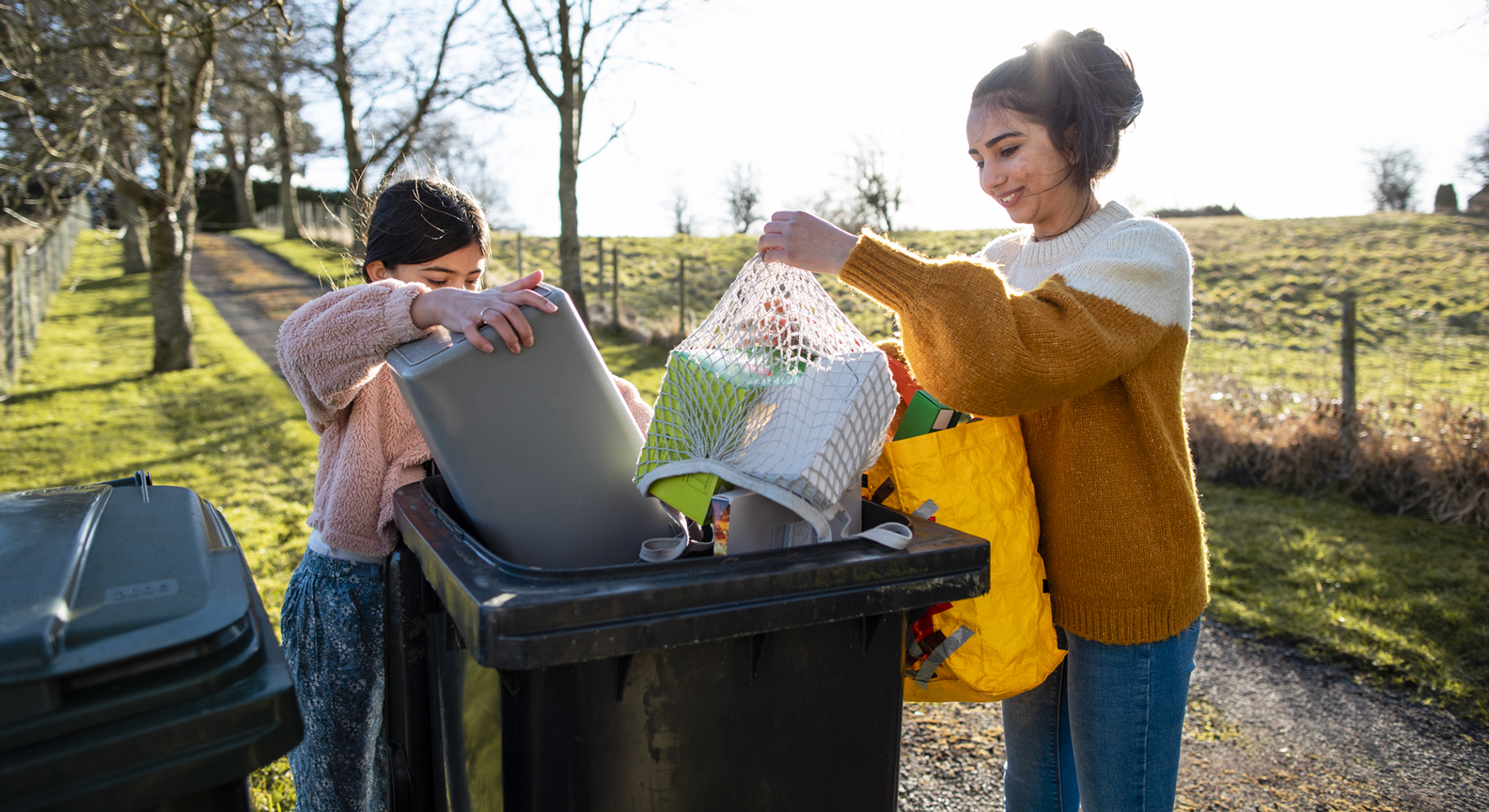 People putting recycling into a wheelie bin