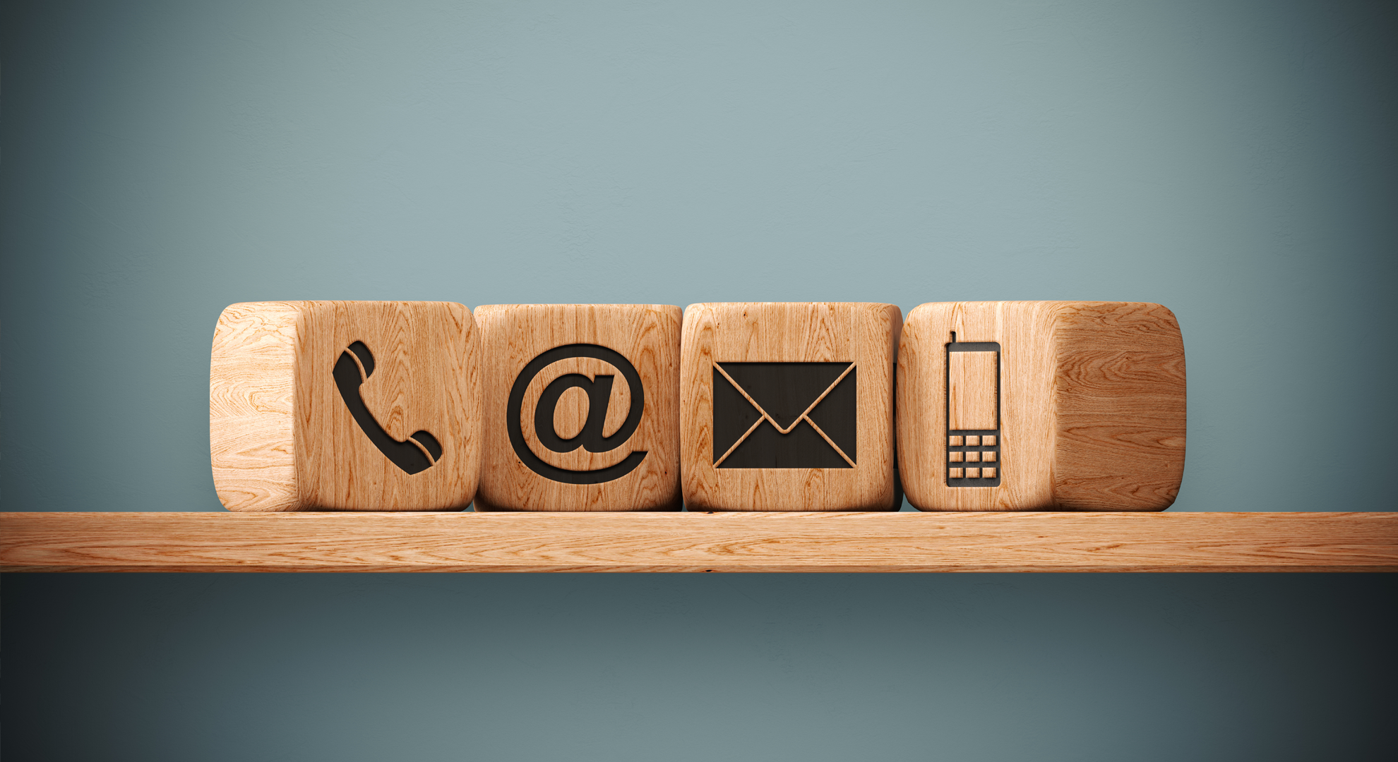 Abstract image of wooden blocks showing symbols for phone, email and mail.