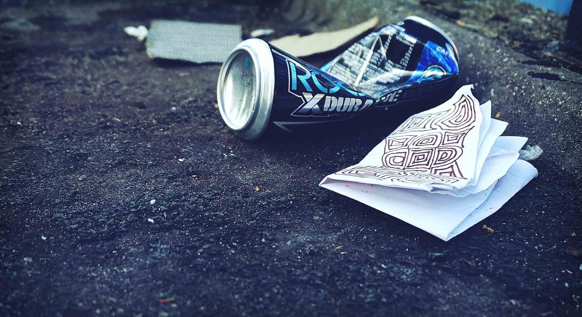 An empty can and napkin left on a pavement