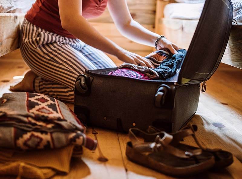 a person putting clothes into a suitcase