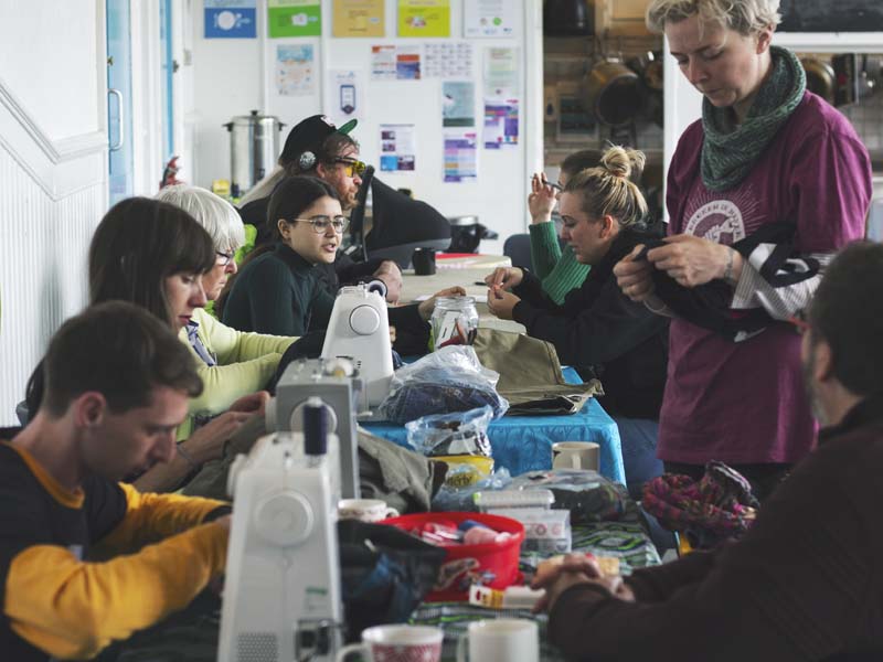 a group of people working with sewing machines at a repair cafe