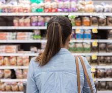 A women is standing facing a supermarket shelf