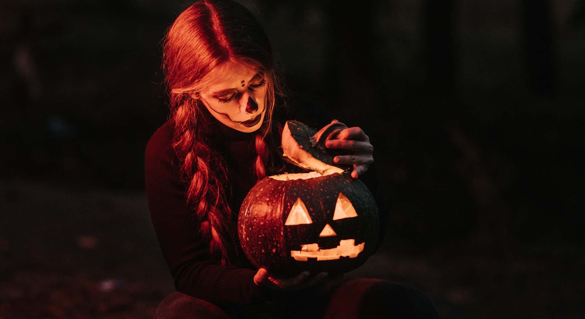 A girl dressed up for Halloween holding a pumpkin