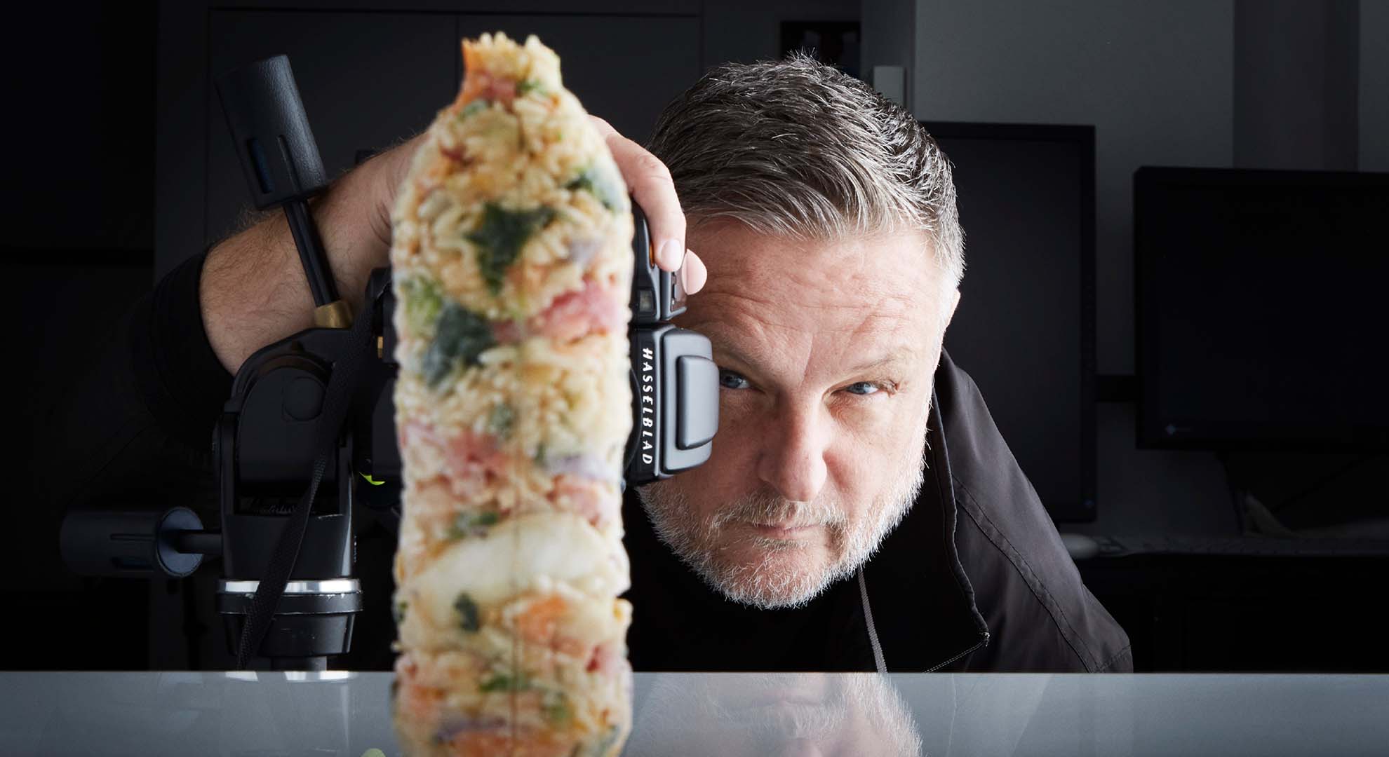Photographer 'Rankin', holding a camera in front of a bottle shape made from food waste