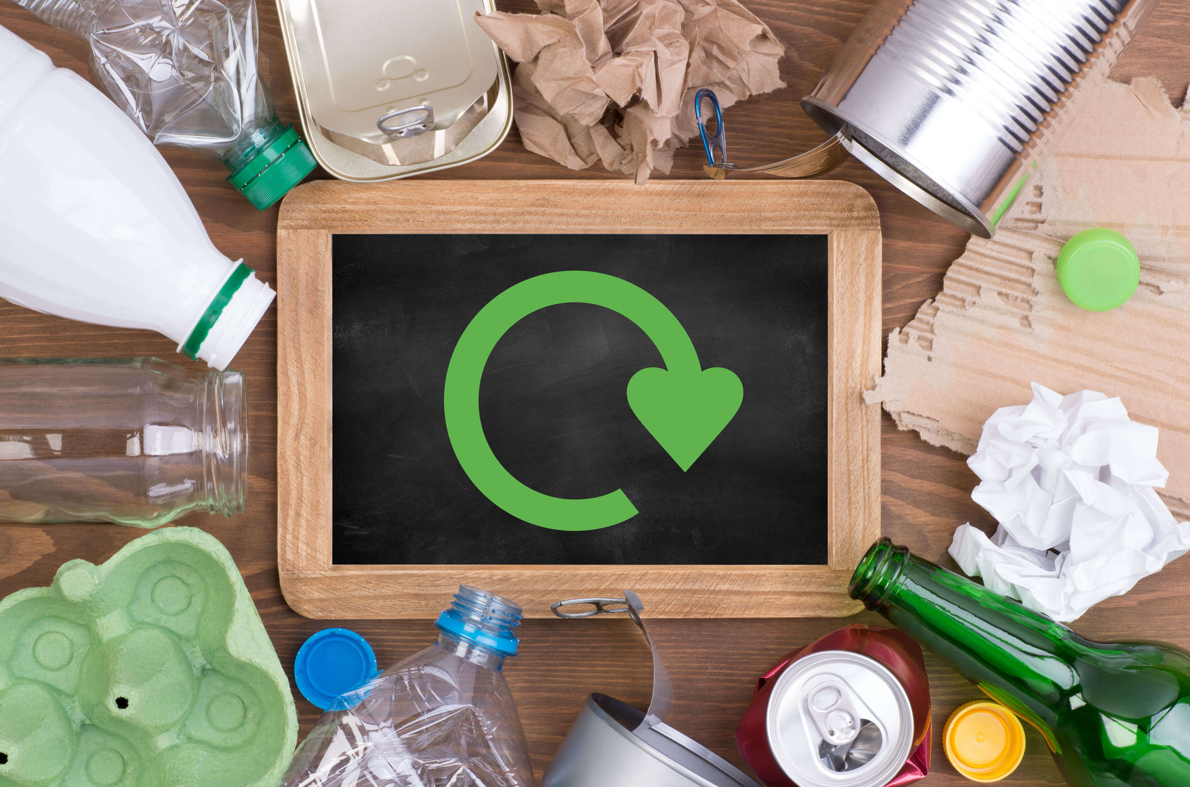 The Recycle for Scotland 'swoosh' logo on a board with various recyclable materials
