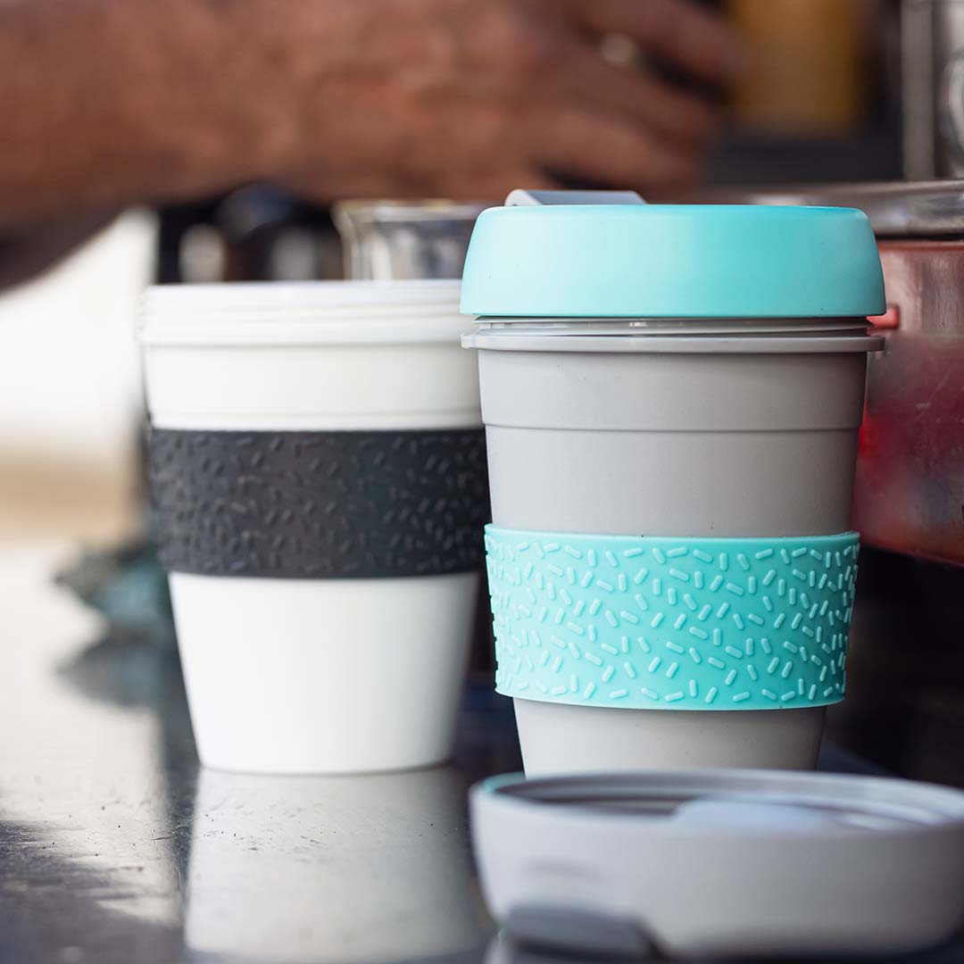 Photo of a barista making coffee in reusable cups in a cafe.