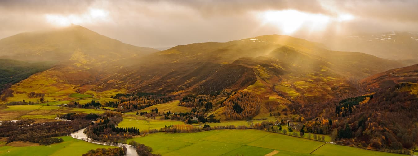 Scottish hills covered in broken sunlight through a cloud.