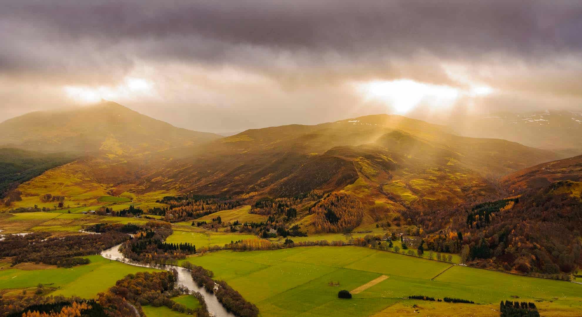 Photo of hills in Scotland with rays of sun piercing the cloud