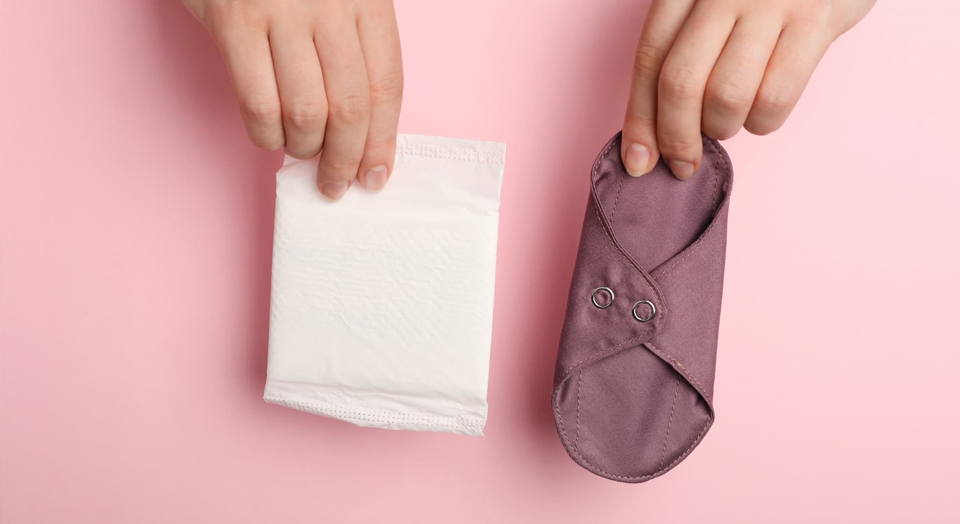 Woman holding disposable and reusable cloth menstrual pads on pink background