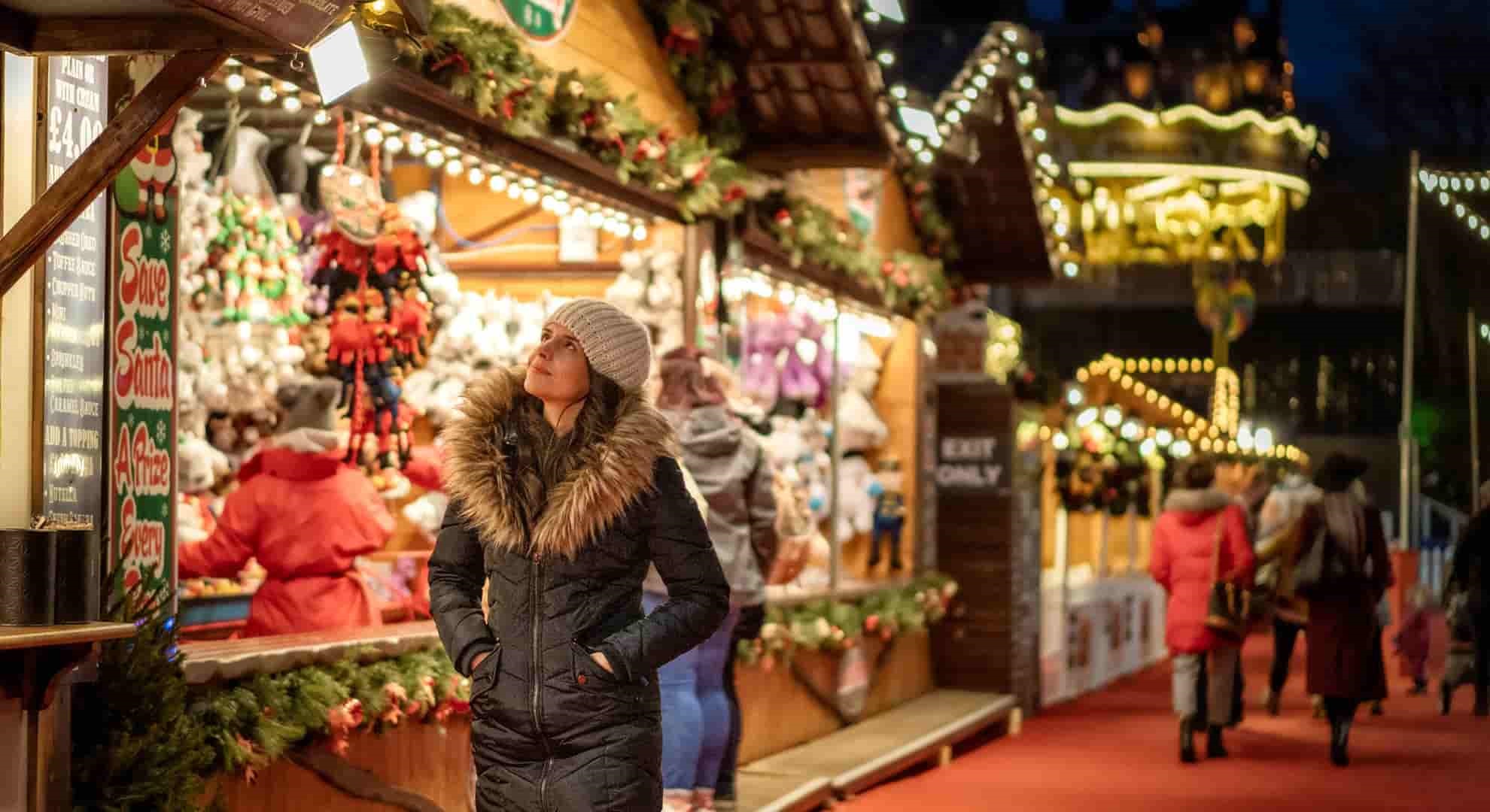 A woman, wrapped up for the weather, looking at Christmas stalls in Edinburgh, Scotland.
