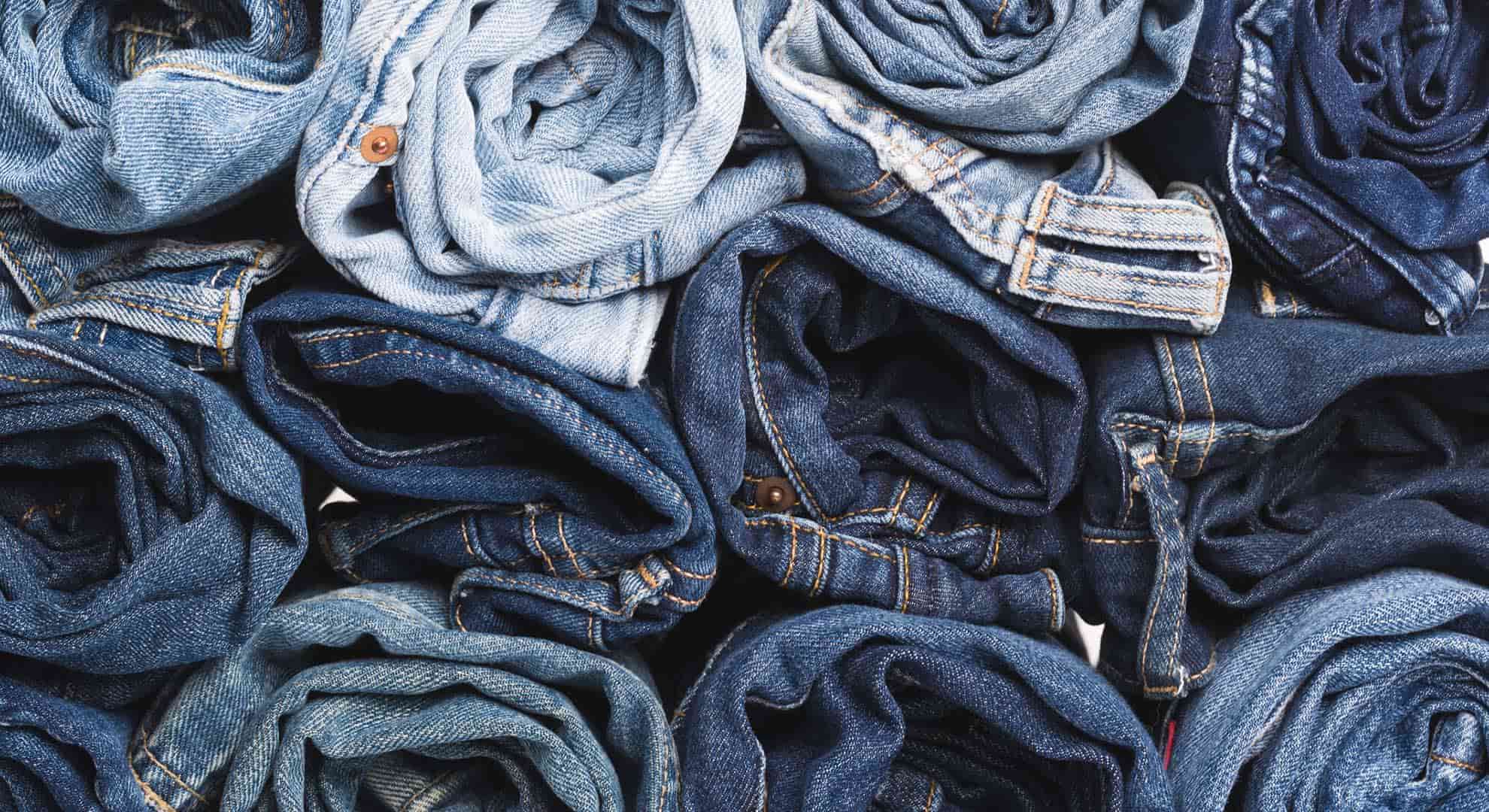 Photo of rolled up denim jeans in rows representing circular textiles