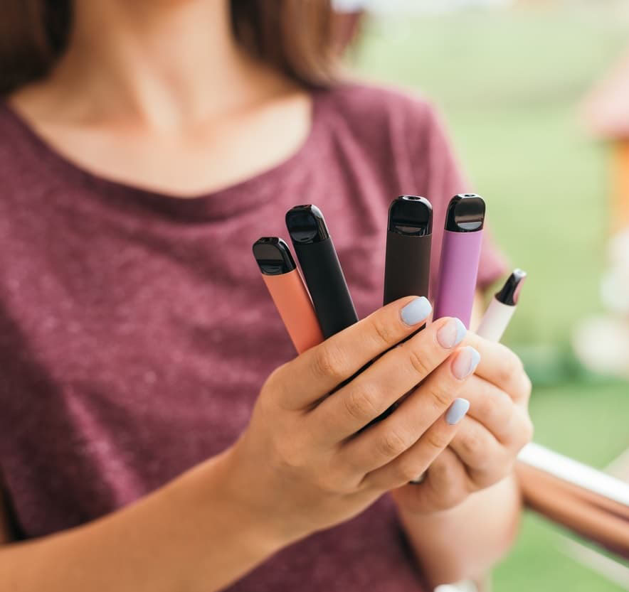 Many different disposable e-cigarettes in hand with