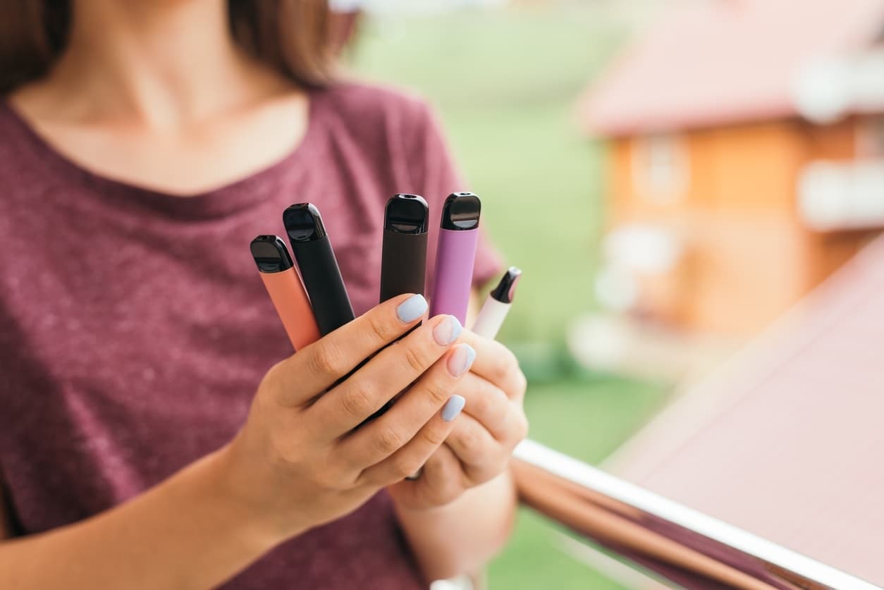 Many different disposable e-cigarettes in hand.