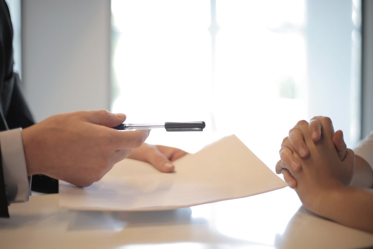 two people signing a contract