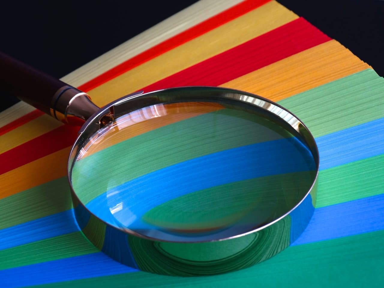 Brown Handle Magnifying Glass on striped multi-coloured paper