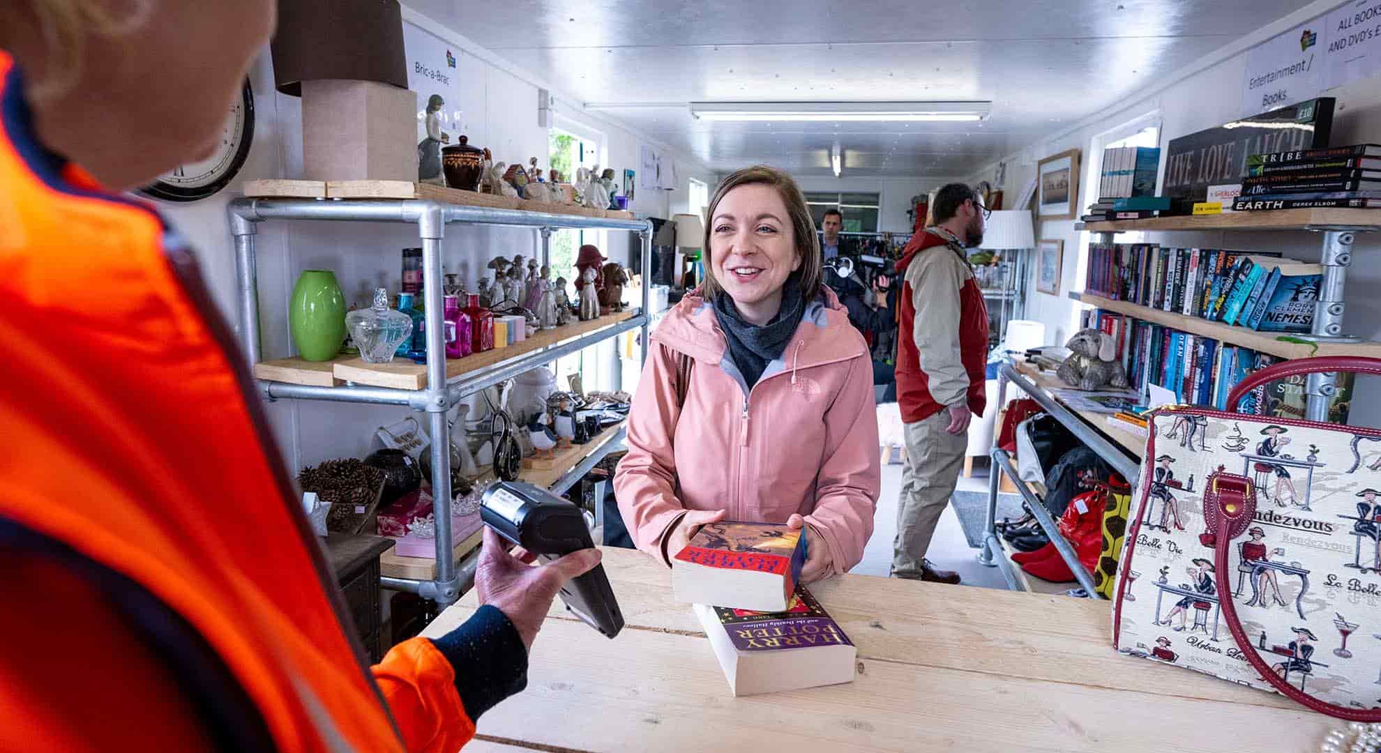 Photo of person purchasing a second-hand book inside Hazlehead Reuse Shop in Aberdeen