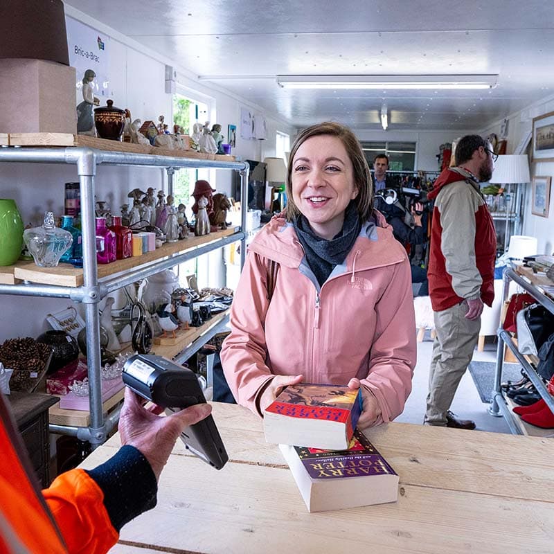 Photo of person purchasing a second-hand book inside Hazlehead Reuse Shop in Aberdeen
