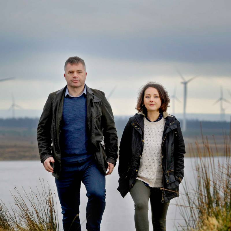 Photo of two people from ReBlade walking outdoors with wind turbines in the background