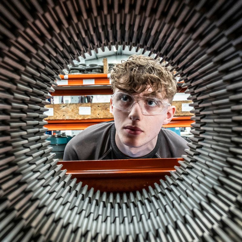 Worker with safety glasses inspecting machine part