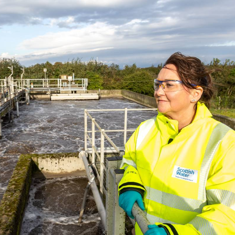 Woman in hi-vis jacket looking at water 