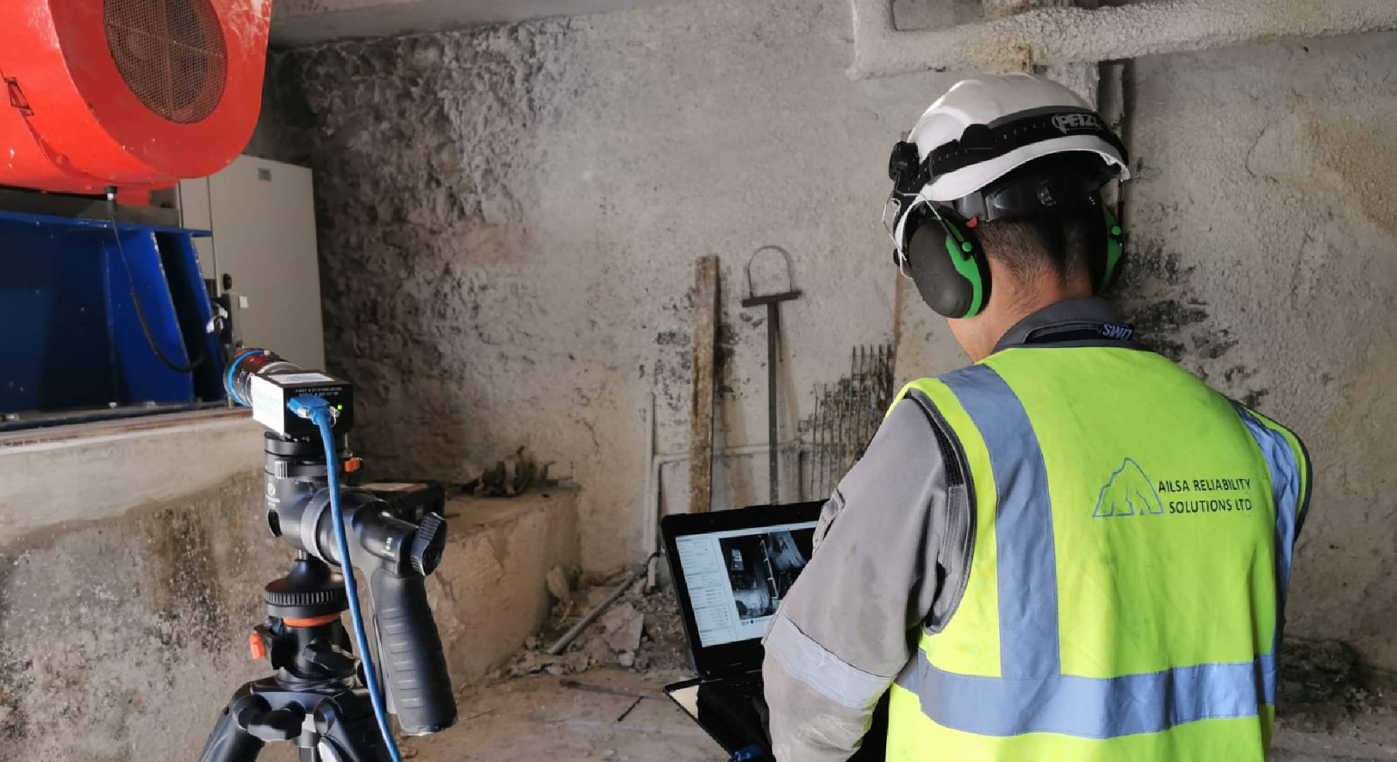 Ailsa Reliability worker in hi-vis on site with laptop