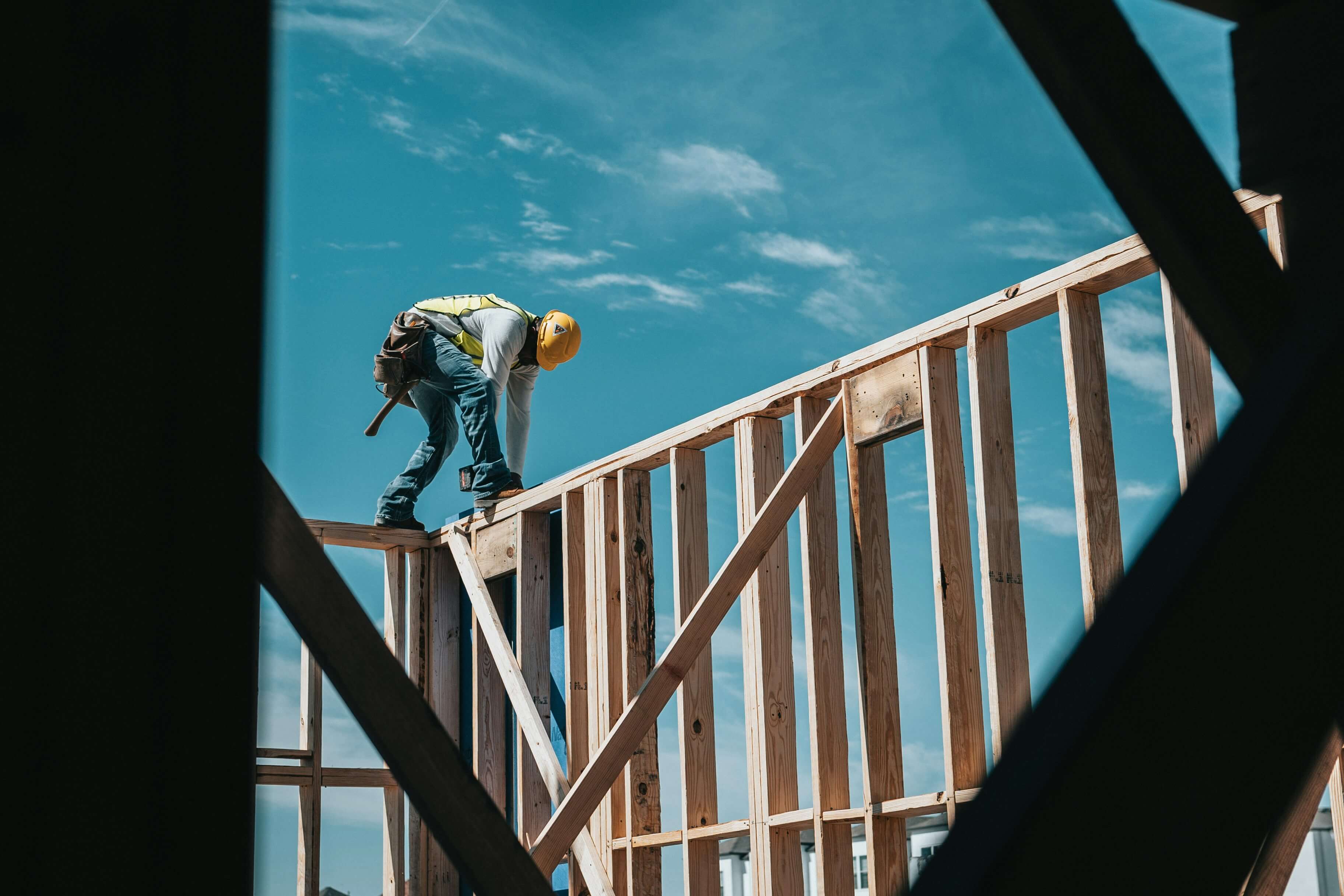 A construction worker standing atop a wooden house frame