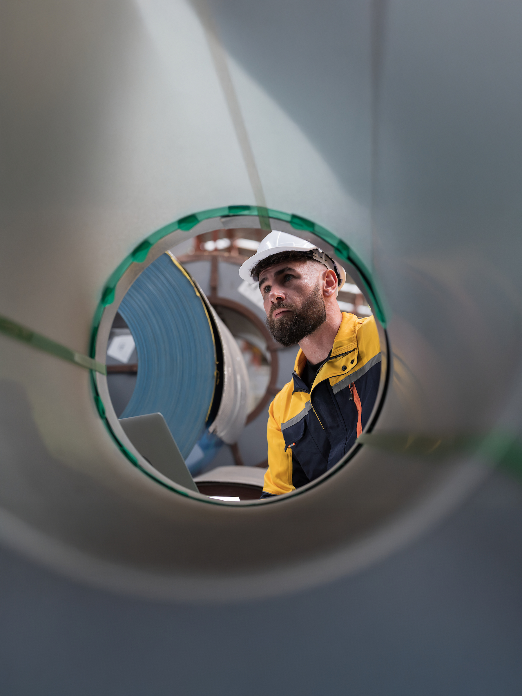 A man working in manufacturing looking inside a cylinder