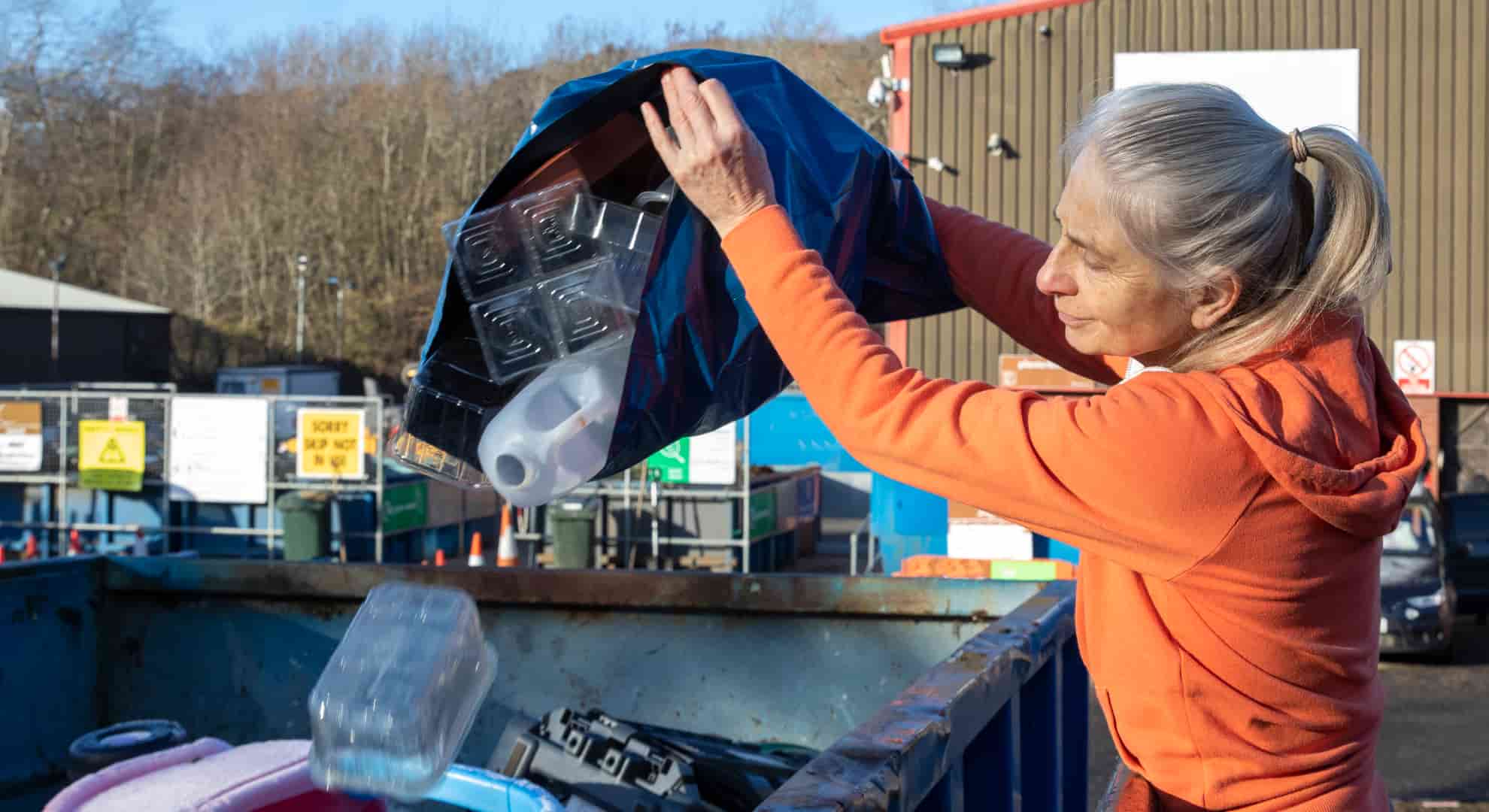 Person using HWRC tipping bag of recyclables into container