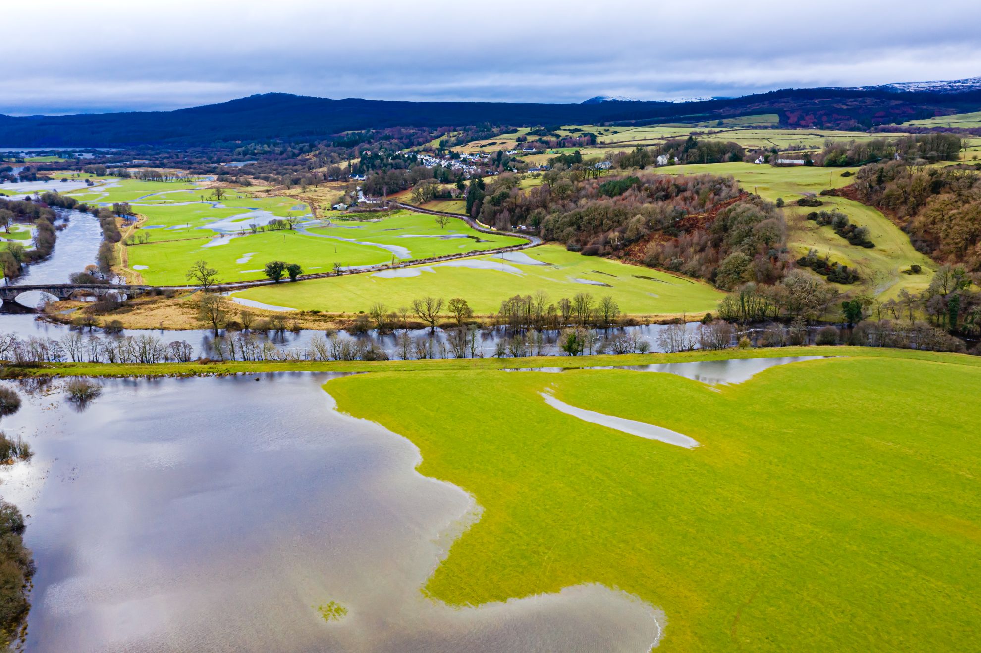 Aerial view of flooded green fields and winding rivers in a rural landscape.