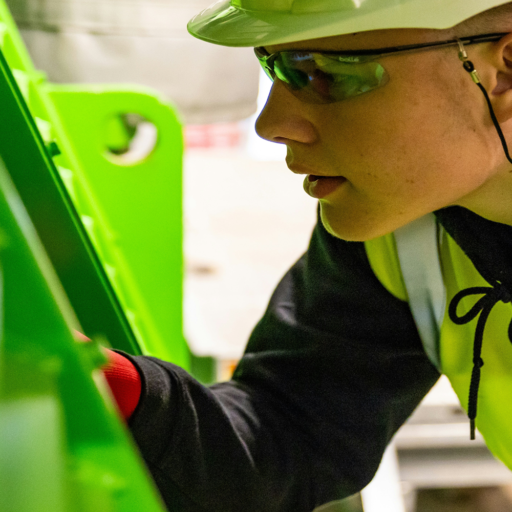 Woman inspecting something wearing hard hat and high viz jacket