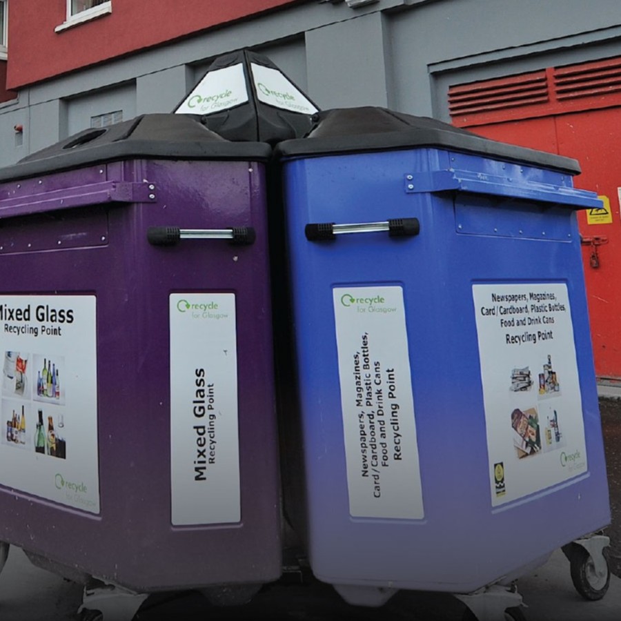 A purple bin and blue bin outside a block of flats