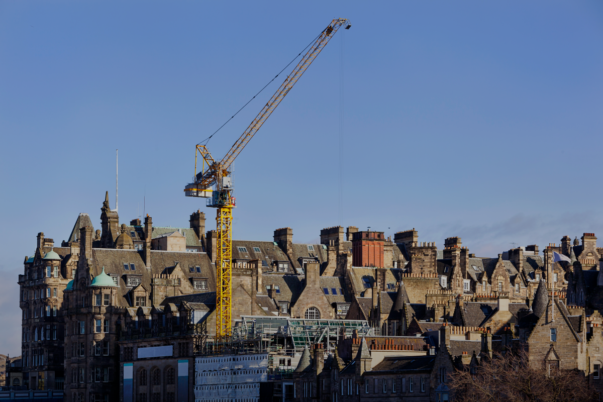 Landscape image of Edinburgh old town with yellow crane in centre 